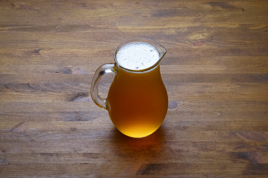 Full pitcher of beer close up on wooden table with copy space
