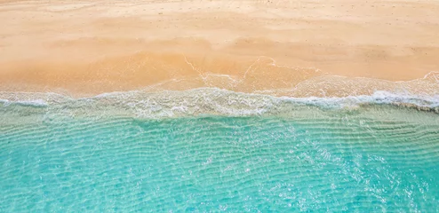 Rolgordijnen Summer seascape beautiful waves, blue sea water in sunny day. Top view from drone. Sea aerial view, amazing tropical nature background. Beautiful bright sea waves splashing and beach sand sunset light © icemanphotos