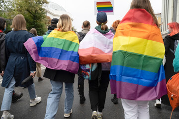 People with LGBT flags are marching. Pride procession along the street of a European city.