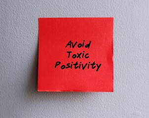 Red paper note stick on office wall with handwritten text AVOID TOXIC POSITIVITY, means optimistic...