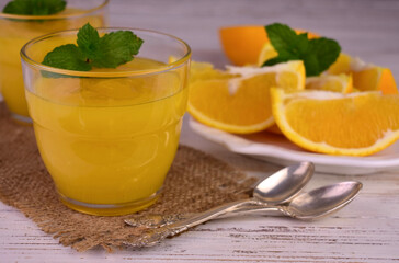 Orange cream (English citrus cream) in a glass on a light wooden background.
