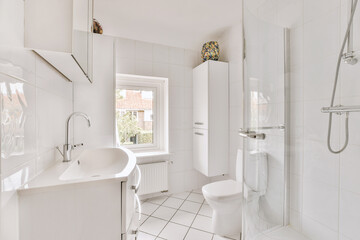 Flush toilet located between sink and shower in small tiled bathroom of contemporary apartment