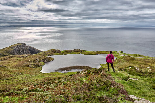 woman hiking on the rock cliffs of Slieve league at the atlantic water way in County Donegal, northern part of Republic of Ireland