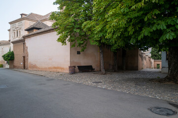 An historic latin street with park bench and a tree, surrounded by cobble stone and walled gardens. Backdrop for graphic resource or decorative copy space.