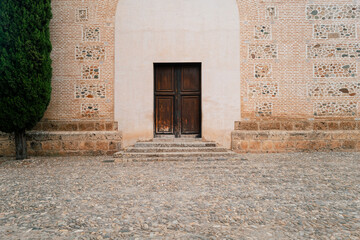 A historic church door in a latin village architecture style, that could be from Europe or America,...