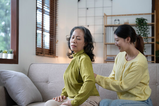 Asian Daughter Giving An Elderly Mother A Relaxing Massage While Sitting On The Sofa