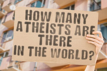 The question " How many atheists are there in the world? " is on a banner in men's hands with blurred background. Spirituality. Science. Nonbeliever. Agnostic. Buddhism. Agnosticism. Asceticism
