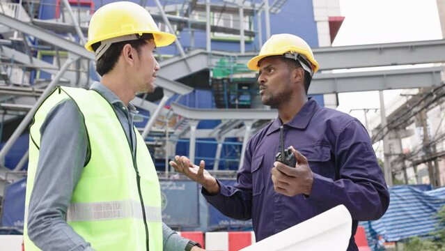 Structural engineers and construction workers are holding blueprints inspecting structure. sky train track construction in city. Blue collar wears a safety hardhat while working on construction site.