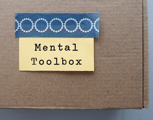 Brown box with stick note written MENTAL TOOLBOX, refers to various tools to tackle different difficult situations, mental tools people use to enhance their self improvement