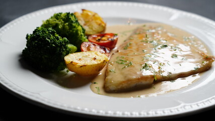 fish dish with sauce on black background