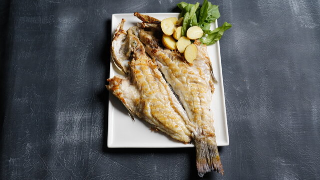 grilled fish dish with sauce on black background