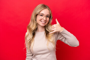 Young English woman isolated on red background With glasses and doing phone gesture