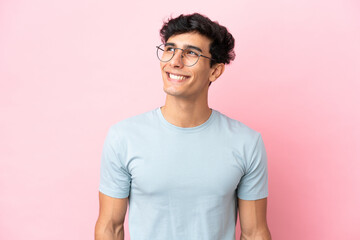 Young Argentinian man isolated on pink background With glasses with happy expression