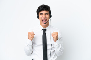 Telemarketer man working with a headset isolated on white background celebrating a victory in winner position