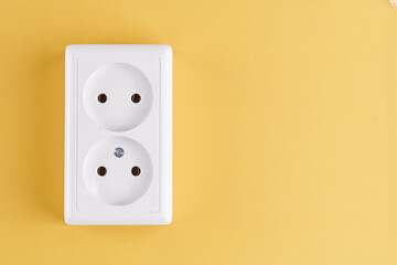 White double socket isolated on yellow background. Electric lighting concept