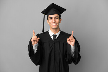 Young Argentinian university graduate isolated on grey background pointing up a great idea