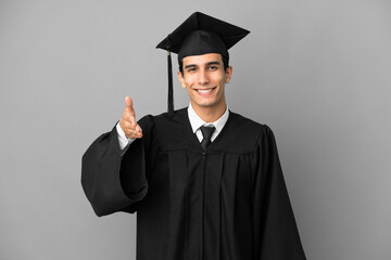 Young Argentinian university graduate isolated on grey background shaking hands for closing a good...