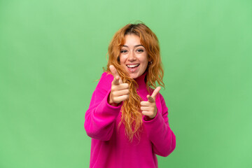 Young caucasian woman isolated on green screen chroma key background surprised and pointing front