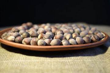 Hazelnuts lie in a heap on a flat plate.