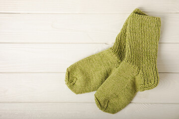 Bright handmade socks on a white wooden background.Knitted warm, winter socks. Wool yarn. winter hobbies. Hobby.Place for text, space for copy.