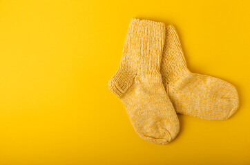 Bright handmade socks on a yellow background.Knitted warm winter socks. Wool yarn. winter hobbies. Hobby.Place for text, space for copy.