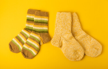 Bright handmade socks on a yellow background.Knitted warm winter socks. Wool yarn. winter hobbies. Hobby.Place for text, space for copy.