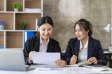 Two young asian accountants working on laptop computer and finance at workplace. Freelance business. Online marketing. ecommerce marketing ideas