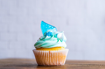Homemade cupcake of blue color placed on wooden desk. Winter and christmas theme, snowflakes on...