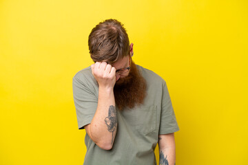 Redhead man with beard isolated on yellow background with headache