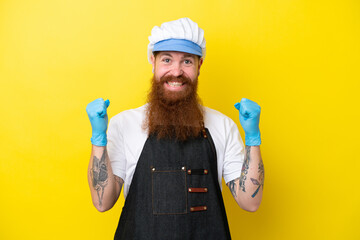 Fishmonger wearing an apron isolated on yellow background celebrating a victory in winner position