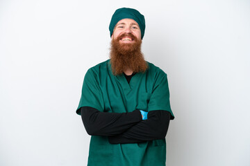 Surgeon redhead man in green uniform isolated on white background keeping the arms crossed in frontal position