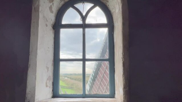 View of spinning old wooden Dutch traditional windmill wings. View from wind mill inside through window. Kinderdijk windmills are UNESCO world heritage site. Kinderdijk, Netherlands