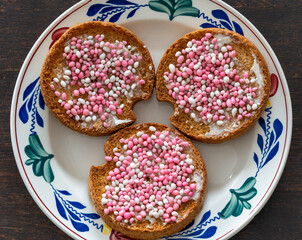 Traditional dutch treat eaten to celebrate the birth of a baby girl called beschuit met muisjes which consists of rusk with white and pink sugary anise seeds isolated on a plate