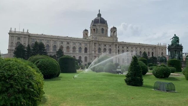 Moving water sprinkles in park, garden in front of Kunsthistorisches Museum (KHM) Wien art museum building. Grass is watered regularly to save it from current heat wave on a hot day. Vienna, Austria