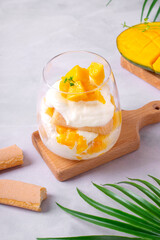 Trifle dessert with mango and ladyfinger cookies served in a glass. Tiramisu cake variation