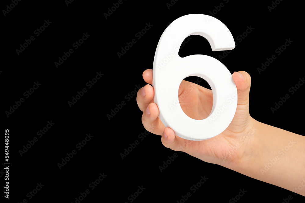 Poster number six in hand isolated on black background. number six in a child's hand holding on a black bac
