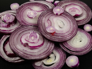 Cross sections of red onions layered on a black background