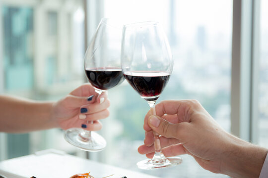 Hands of young couple holding with glass of wine cheer together in anniversary at restaurant for celebration, man and woman date with romantic and relationship, valentine and holiday concept.