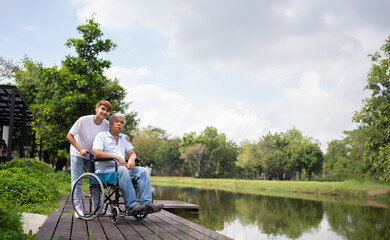Asian careful caregiver or nurse hold the patient hand and encourage the patient in a wheelchair. Concept of happy retirement with care from a caregiver and Savings and senior health insurance.