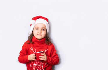 Cute caucasian kid girl in red Santa's hat holding red mug or cup empty copy space for design or text. Banner. Christmas mockup template.