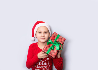 Caucasian kid child in Santa hat holds gift box on light background. Copy space for design or text. Banner. Christmas New Year mockup template.