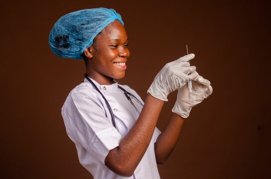 Smiling Nigerian female medic with a filled syringe isolated on a brown background