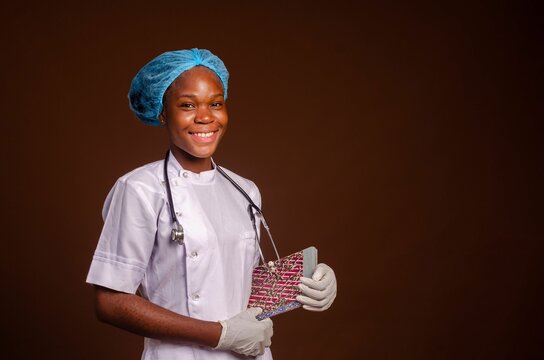 Smiling Nigerian female medic with a stethoscope isolated on a brown background