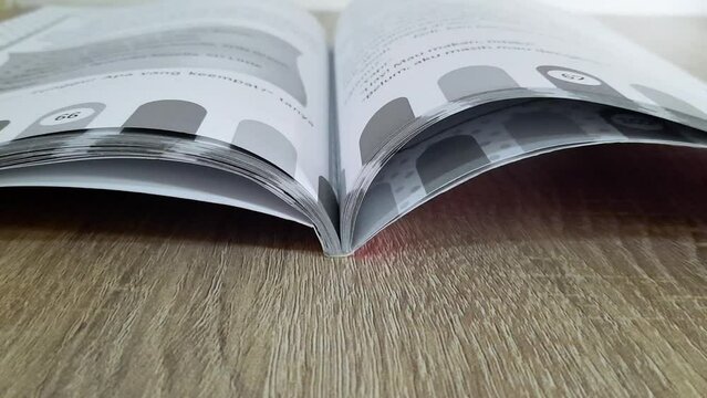 Close-up of turning the pages of the book. A book on the wooden table.