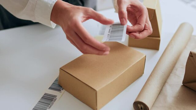 The work process of a parcel packer in a warehouse sticking a barcode sticker on a prepared package box for sending by courier for delivery, E-commerce selling online delivery service
