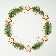 Christmas composition. Christmas wreath made of fir tree branches and star shaped cookies on white background. Flat lay, top view, copy space