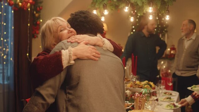 Happy diverse family arriving for dinner party celebrating Christmas or New Year at decorated cozy home. They hugging, talking and smiling. Warm atmosphere of family holidays. Christmas Eve.