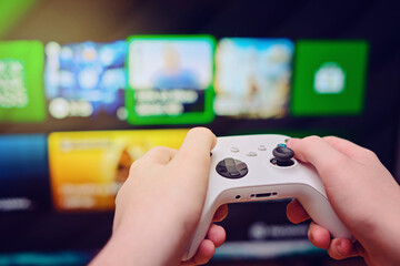 young man hold joystick and playing video game at home in front of television with play game concole. man hold gamepad in hands in front of tv screen. © Вячеслав