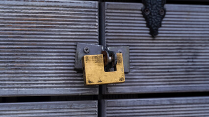 Fototapeta na wymiar A close-up of a gold-colored metal padlock closes a wooden door. Locked door. wooden door with padlock.