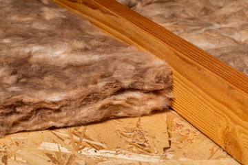 Fiberglass insulation in attic of house. Home energy savings, heating and cooling costs and...